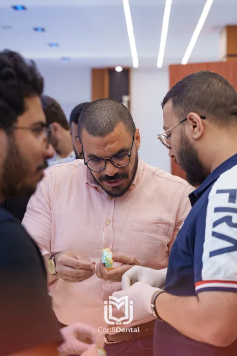 An instructor showing a small implant model to two participants